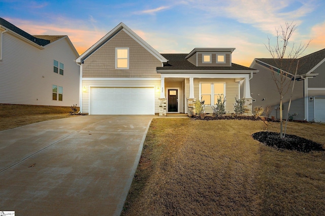 craftsman-style home with covered porch, a garage, and a lawn