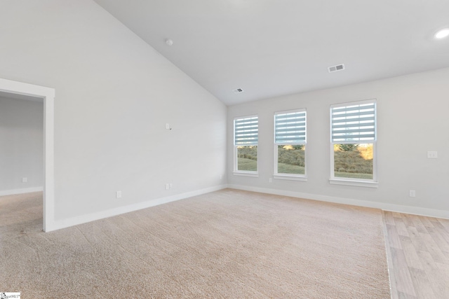 empty room with high vaulted ceiling and light colored carpet