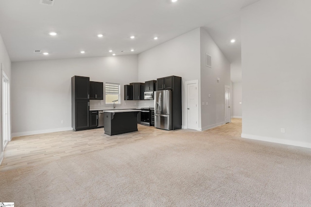 kitchen with light carpet, a breakfast bar area, stainless steel appliances, a high ceiling, and a kitchen island