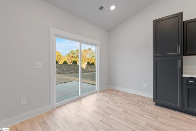 unfurnished dining area featuring light hardwood / wood-style floors and vaulted ceiling