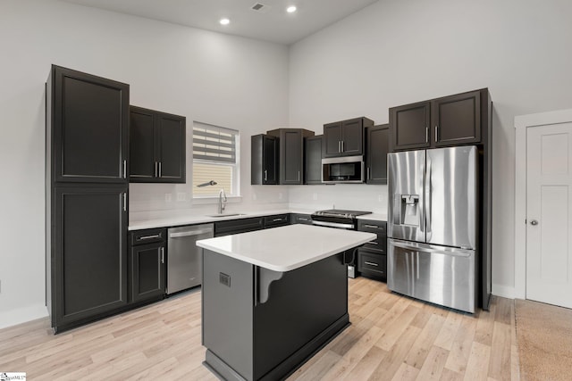 kitchen with a center island, a kitchen bar, sink, a high ceiling, and stainless steel appliances