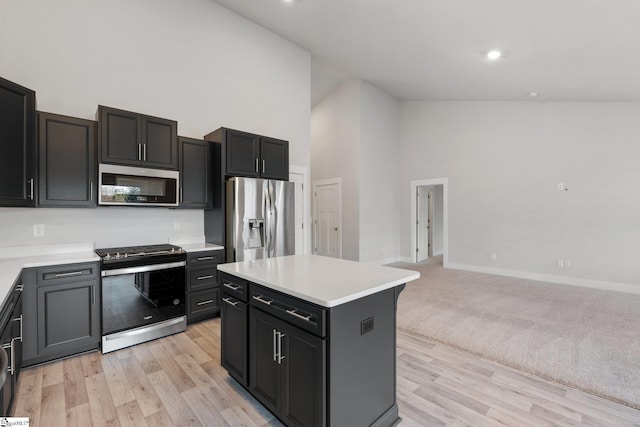 kitchen featuring high vaulted ceiling, light hardwood / wood-style floors, stainless steel appliances, and a kitchen island