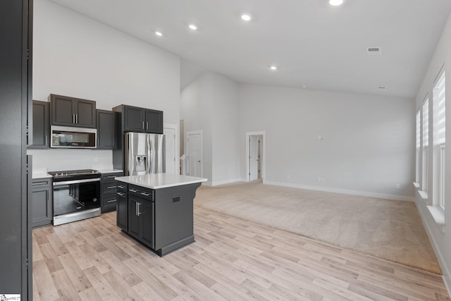 kitchen featuring light wood-type flooring, stainless steel appliances, high vaulted ceiling, and a center island