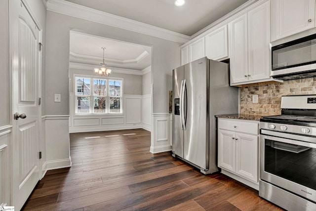 kitchen featuring dark stone counters, white cabinets, stainless steel appliances, and a notable chandelier