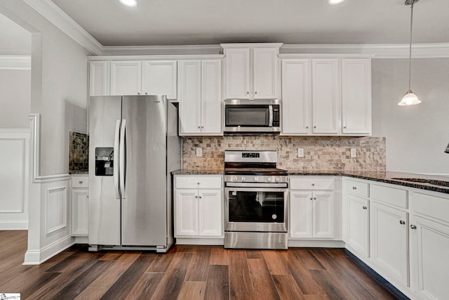 kitchen featuring white cabinetry, dark stone countertops, stainless steel appliances, and hanging light fixtures