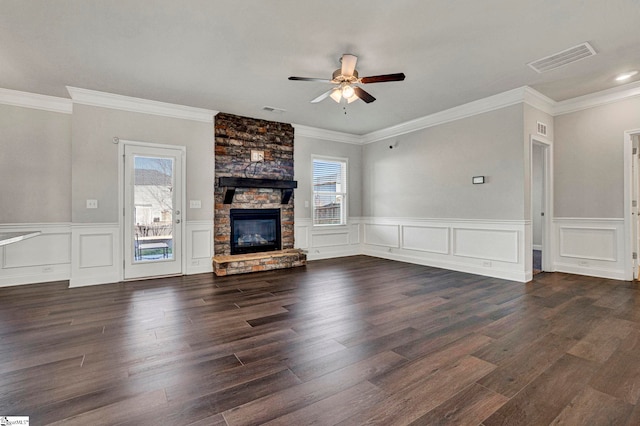 unfurnished living room featuring ceiling fan, dark hardwood / wood-style floors, crown molding, and a stone fireplace