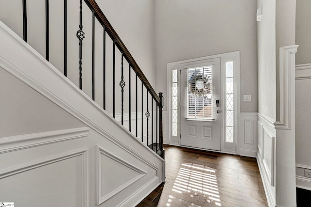 entryway with dark hardwood / wood-style floors and a towering ceiling