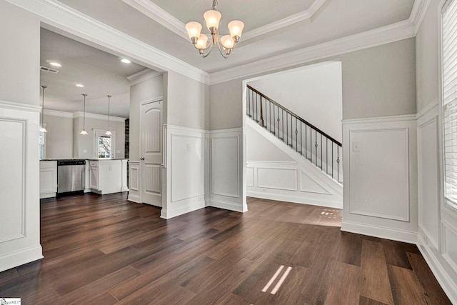 interior space with dark hardwood / wood-style floors, a raised ceiling, ornamental molding, and a notable chandelier