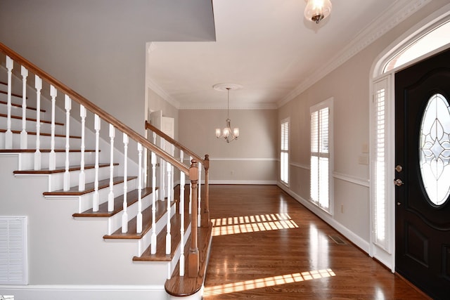 entryway with dark hardwood / wood-style flooring, an inviting chandelier, and ornamental molding