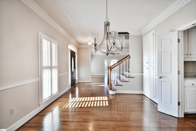 entryway with dark hardwood / wood-style floors, a chandelier, and ornamental molding