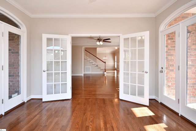 interior space with dark hardwood / wood-style flooring, crown molding, ceiling fan with notable chandelier, and french doors