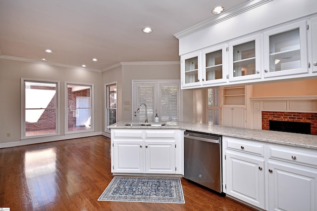 kitchen featuring white cabinetry, sink, a brick fireplace, stainless steel dishwasher, and crown molding