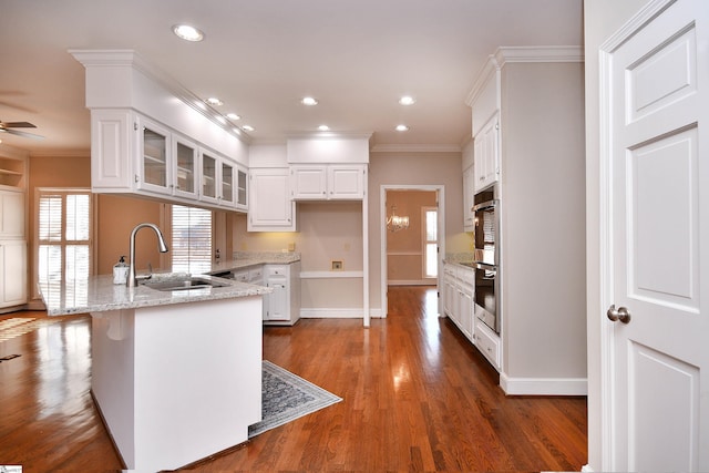 kitchen with white cabinets, dark wood-type flooring, sink, light stone counters, and crown molding