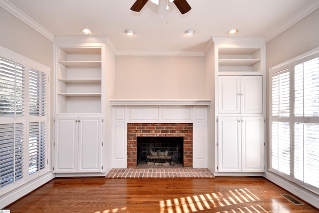 unfurnished living room with a brick fireplace, built in shelves, and hardwood / wood-style flooring