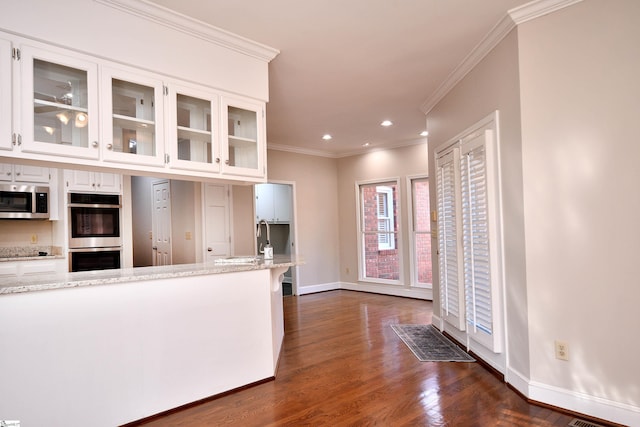 kitchen featuring light stone counters, white cabinetry, appliances with stainless steel finishes, and crown molding