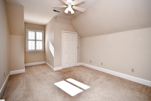 additional living space featuring ceiling fan, light colored carpet, and vaulted ceiling