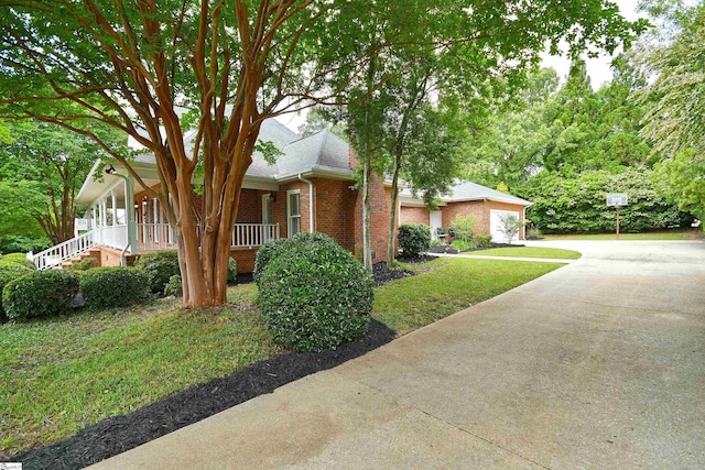 view of front of home featuring a front yard, covered porch, and a garage