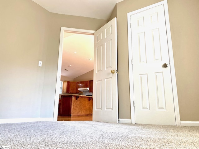 corridor with vaulted ceiling and carpet flooring