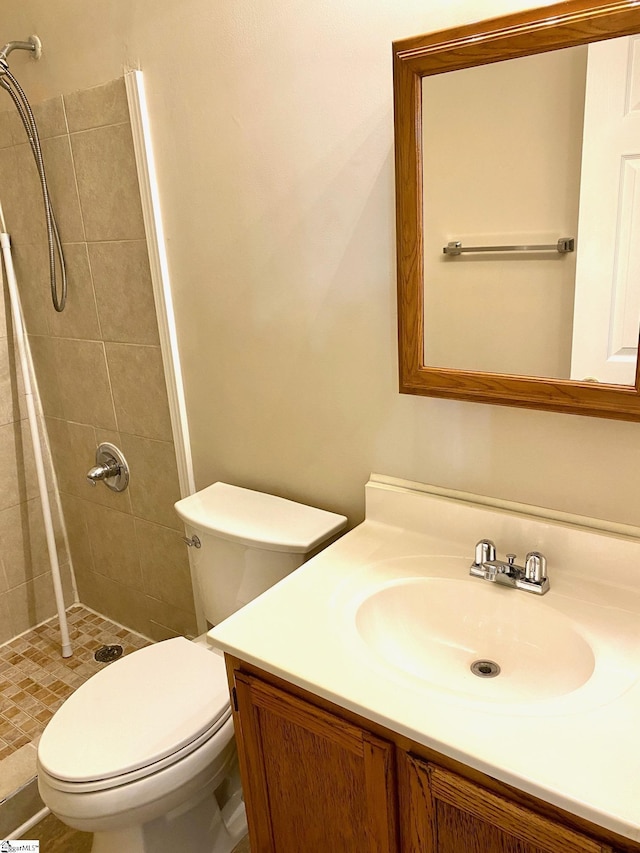 bathroom featuring toilet, vanity, and a tile shower