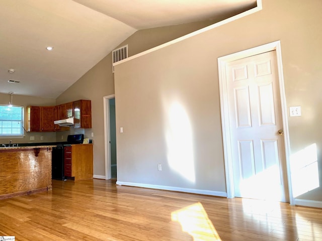 kitchen featuring light wood-type flooring, black stove, vaulted ceiling, and sink