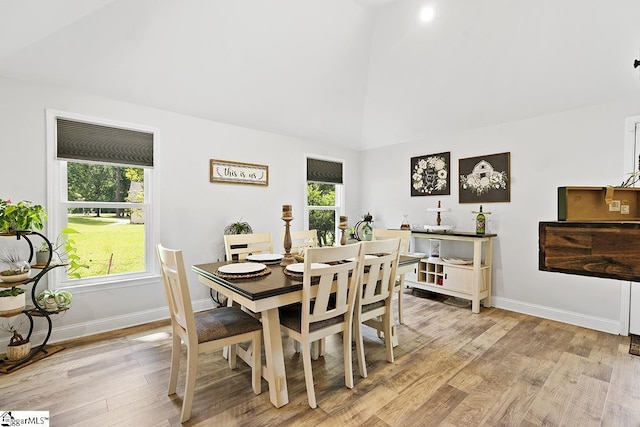 dining area with high vaulted ceiling, light hardwood / wood-style flooring, and a healthy amount of sunlight