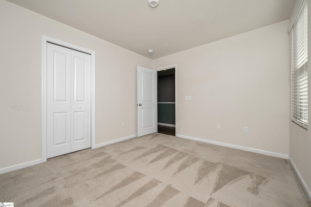 unfurnished bedroom with a closet and light carpet