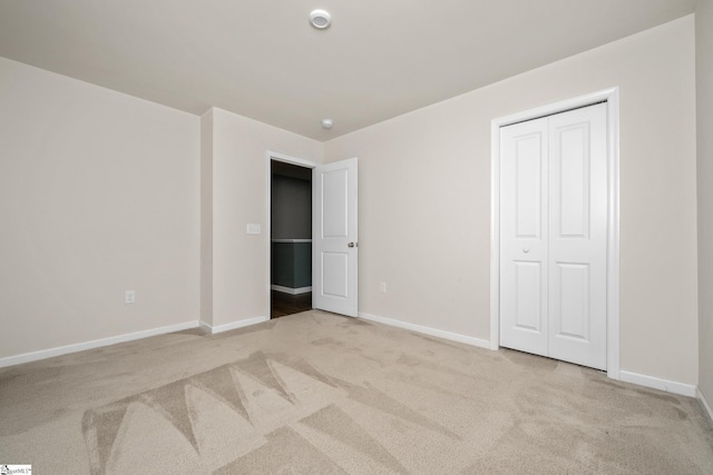 unfurnished bedroom with a closet and light colored carpet