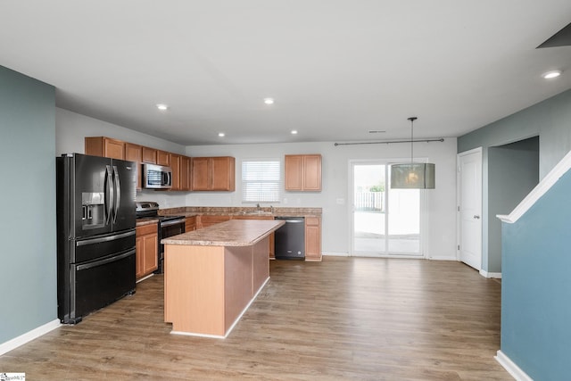 kitchen featuring appliances with stainless steel finishes, light hardwood / wood-style floors, decorative light fixtures, and a center island