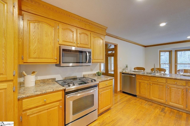 kitchen with sink, crown molding, light hardwood / wood-style flooring, light stone countertops, and stainless steel appliances