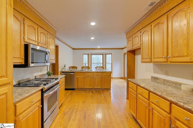 kitchen with appliances with stainless steel finishes, crown molding, light hardwood / wood-style floors, and light stone countertops