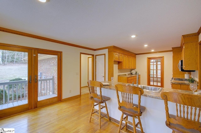 kitchen featuring a healthy amount of sunlight, light wood-type flooring, sink, and ornamental molding