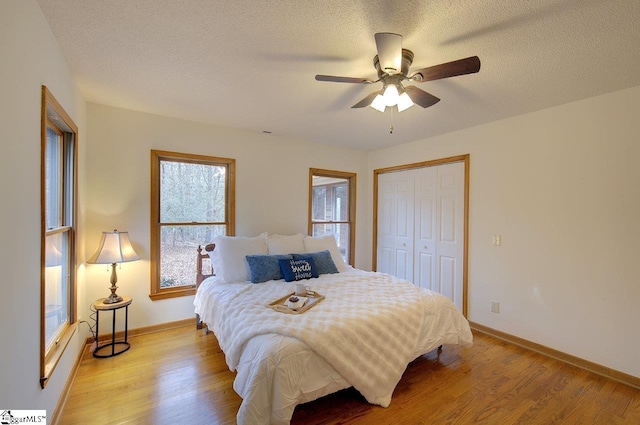 bedroom featuring a textured ceiling, ceiling fan, a closet, and light hardwood / wood-style flooring