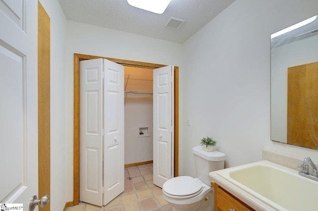 bathroom with toilet, a textured ceiling, tile patterned floors, and vanity