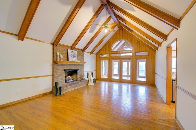 unfurnished living room featuring beamed ceiling, light hardwood / wood-style floors, a fireplace, and high vaulted ceiling