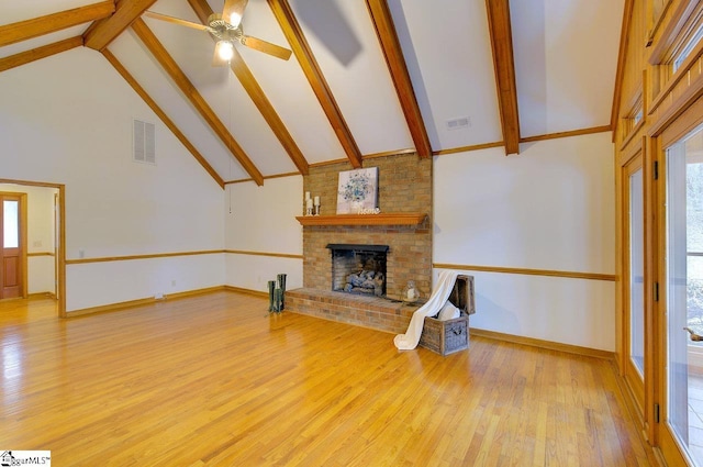 unfurnished living room featuring high vaulted ceiling, plenty of natural light, light hardwood / wood-style flooring, and a fireplace