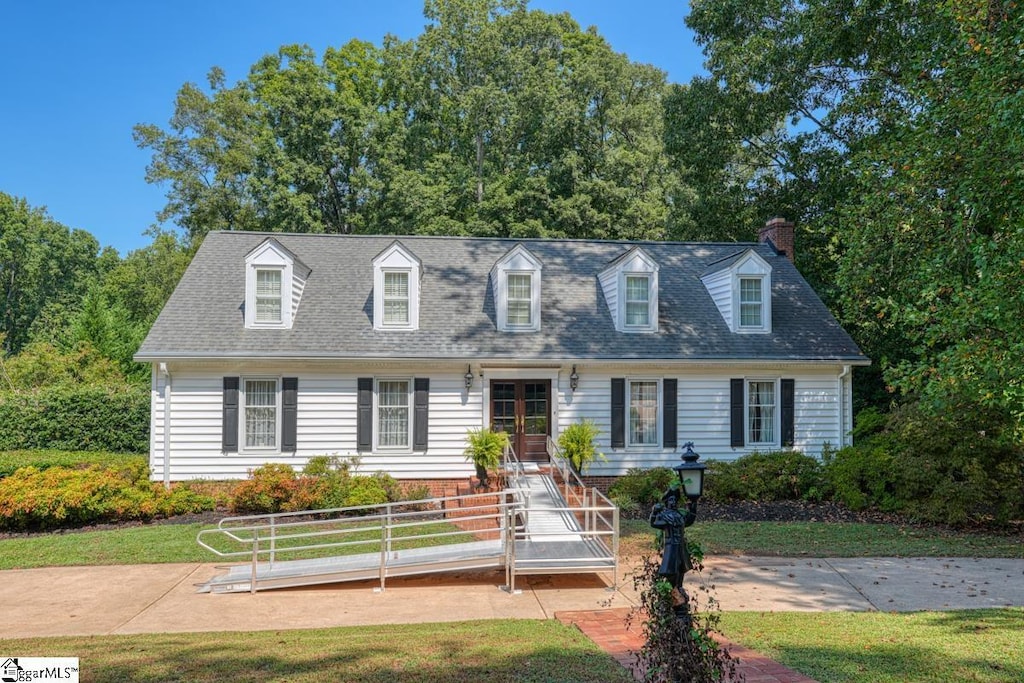 cape cod home featuring a front yard