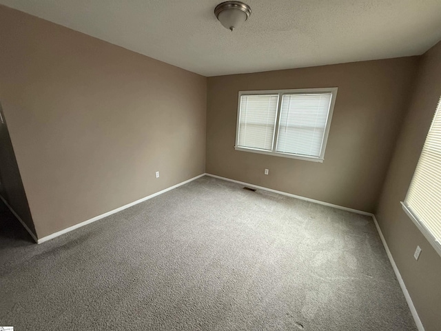 carpeted spare room featuring a textured ceiling