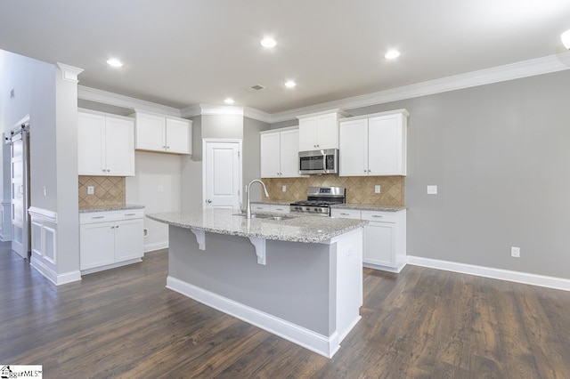 kitchen with sink, white cabinetry, stainless steel appliances, and an island with sink