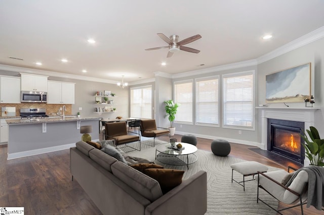 living room with baseboards, dark wood-style floors, a fireplace with flush hearth, crown molding, and ceiling fan with notable chandelier