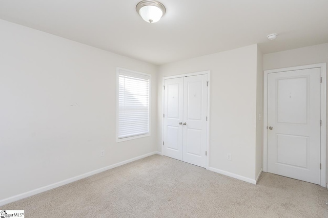 unfurnished bedroom with light carpet and a closet