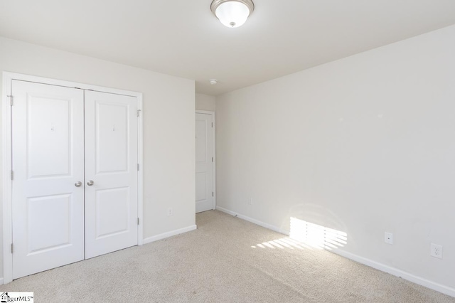 unfurnished bedroom featuring light colored carpet and a closet