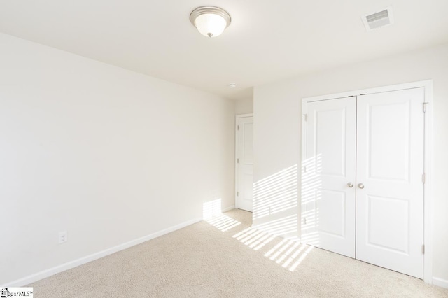 unfurnished bedroom featuring a closet and light carpet