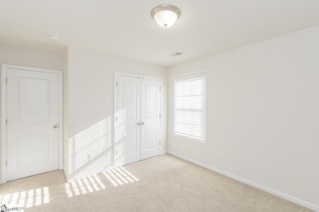 unfurnished bedroom with light carpet and a closet