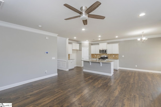 kitchen with dark hardwood / wood-style floors, white cabinetry, light stone countertops, appliances with stainless steel finishes, and an island with sink