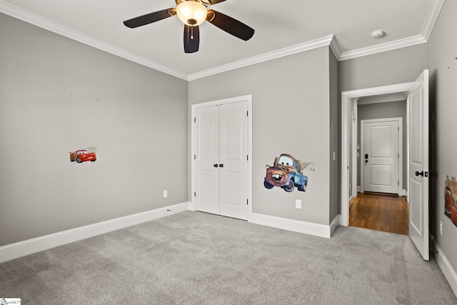 unfurnished bedroom with ceiling fan, crown molding, a closet, and light carpet