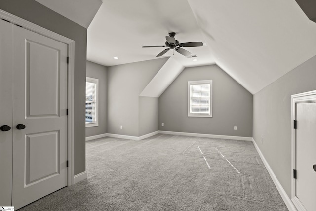 additional living space featuring ceiling fan, plenty of natural light, light colored carpet, and lofted ceiling