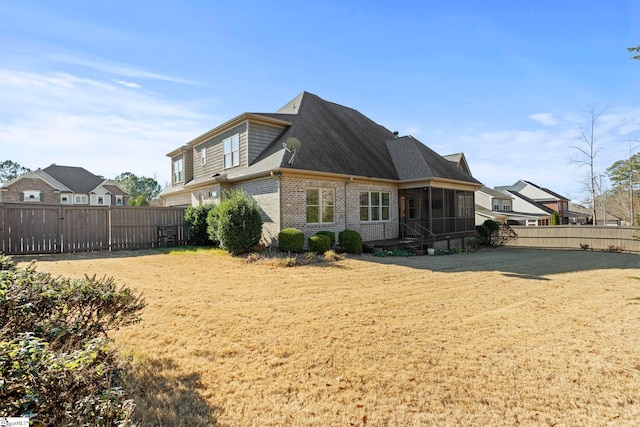 rear view of house with a yard and a sunroom