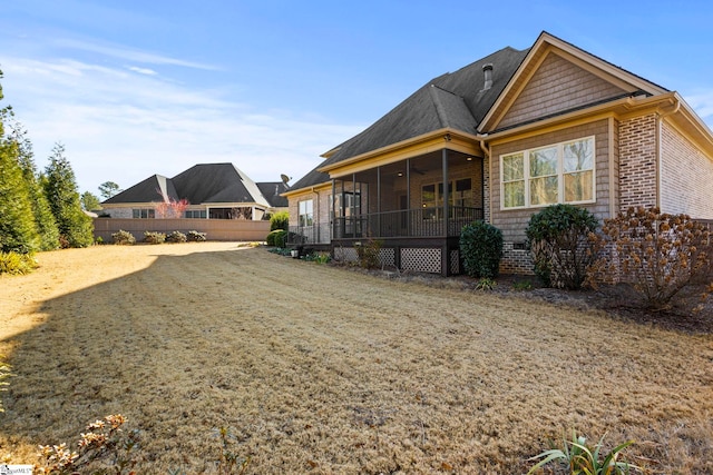 rear view of property featuring a sunroom and a yard