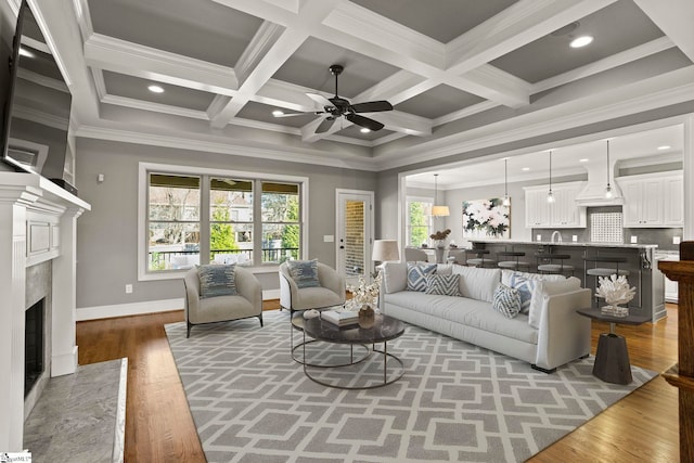 living room with beam ceiling, wood-type flooring, crown molding, and coffered ceiling