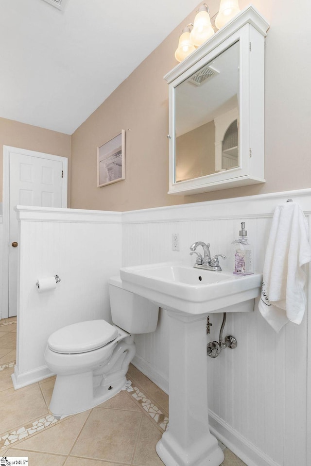 bathroom with tile patterned floors, toilet, and wooden walls